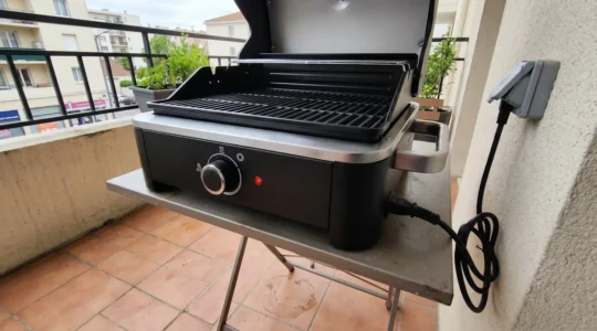 Famille utilisant un barbecue électrique sur une terrasse urbaine lors d'un repas convivial